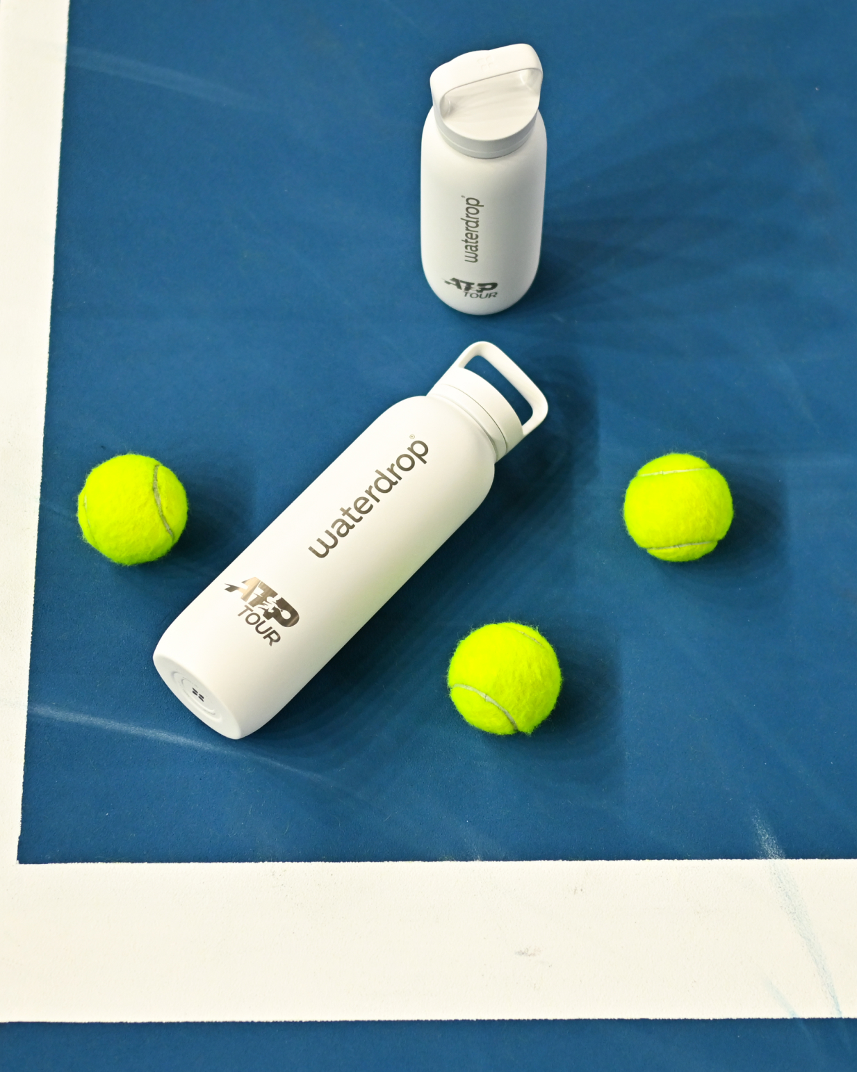 Official ATP Tour waterdrop all-purpose Thermo with Spout Lid, shown with tennis balls and water bottles, ideal for hydration on and off the court.