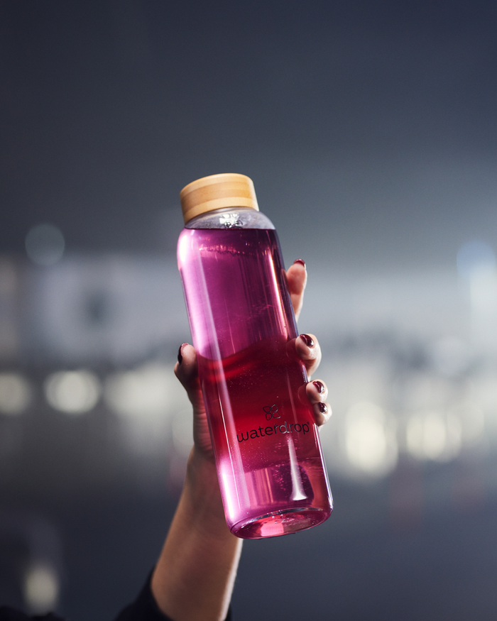 Hand holding a bottle of Microlyte BERRY, a sports drink providing essential electrolytes for activities like pilates, spinning, and yoga.
