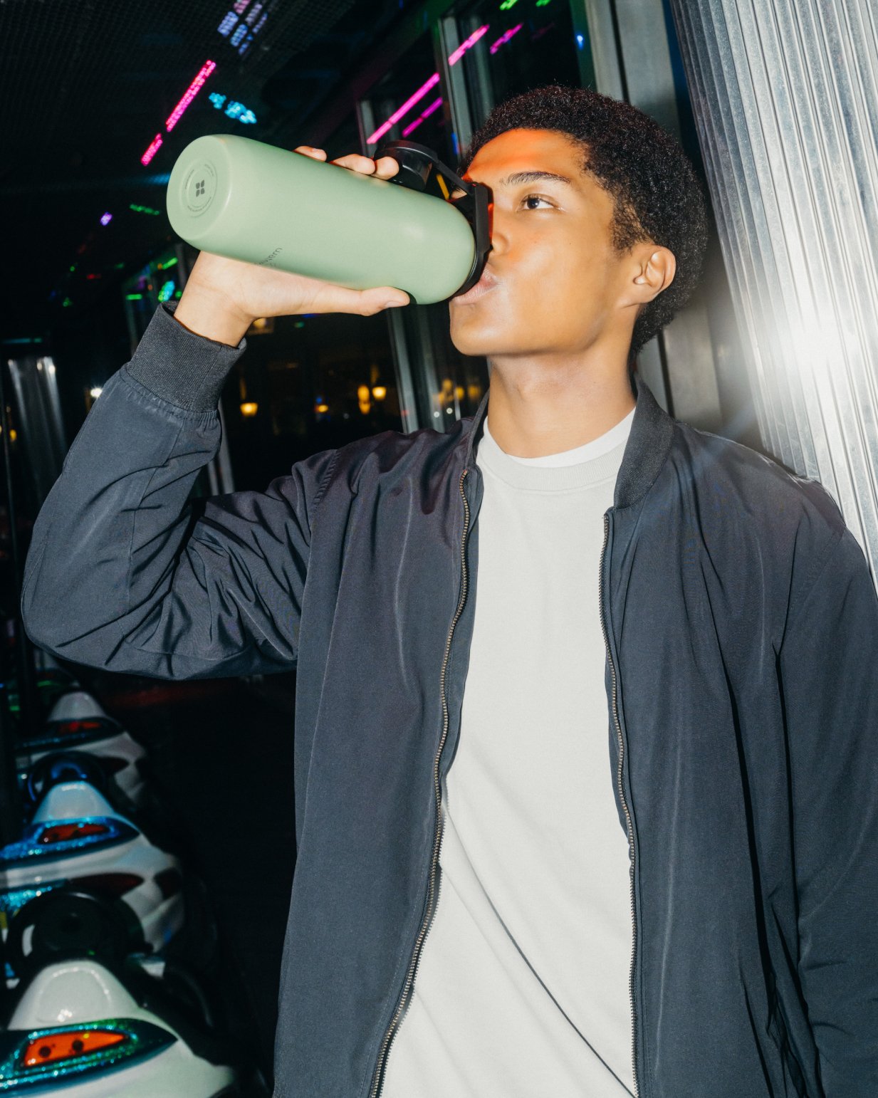 A man drinking from the green All-Purpose Thermo bottle with Swing Lid, highlighting its practical design for easy hydration.