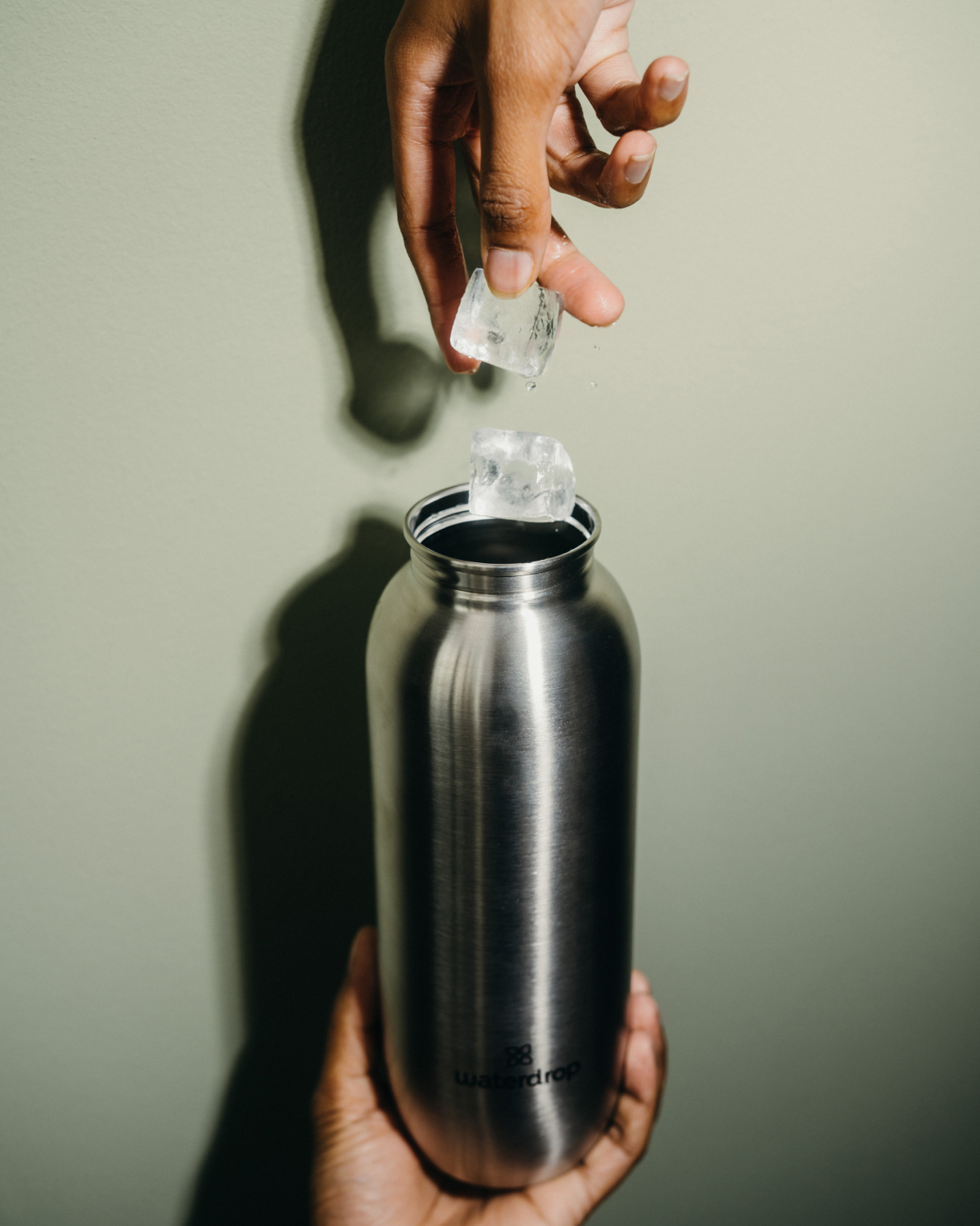 Person pouring ice into the All-Purpose Ultralight Bottle with Spout Lid, emphasizing its lightweight design and versatility for hydration on the go.