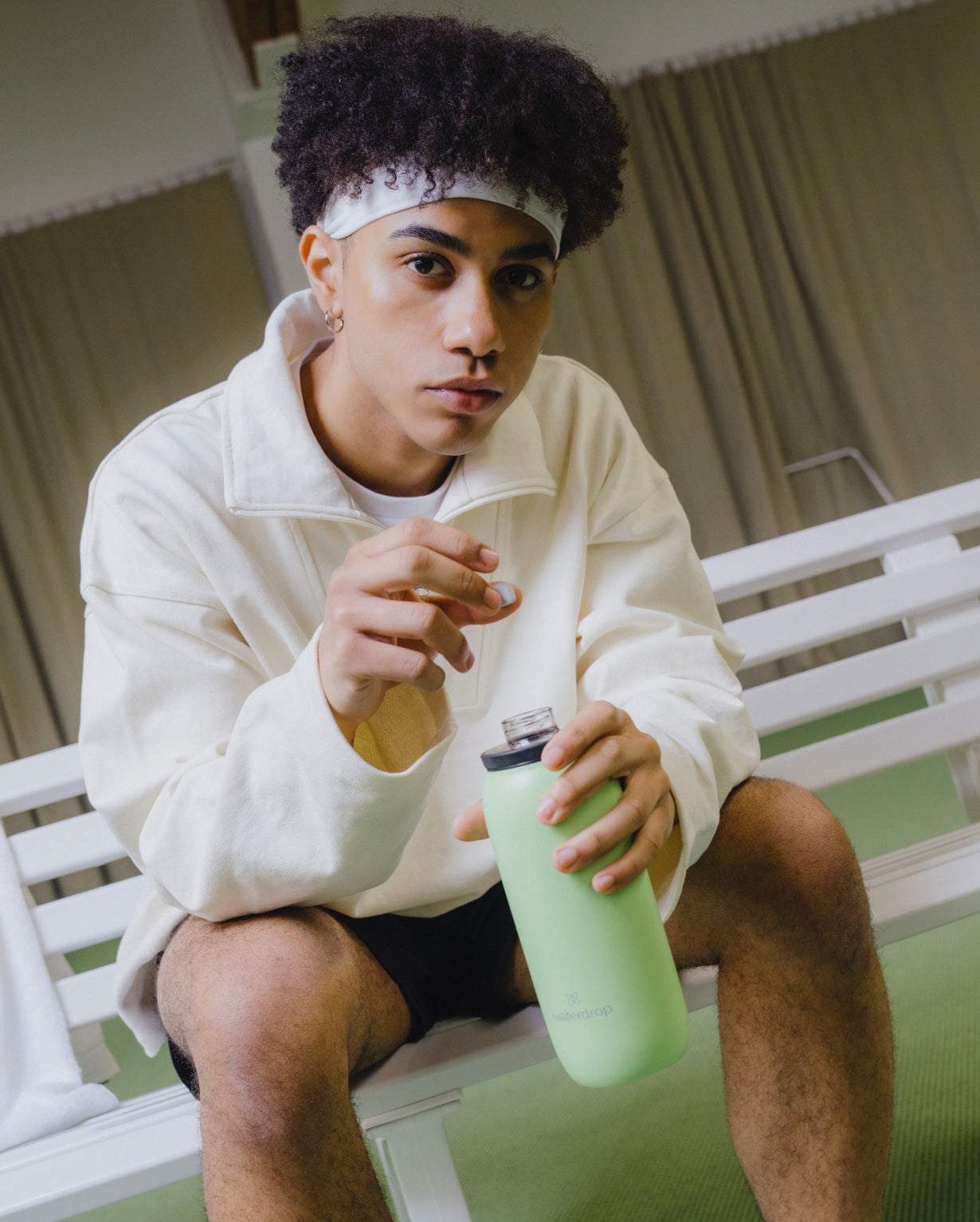 Man sitting on a bench holding the All-Purpose Thermo Bottle with Spout Lid, emphasizing its large opening for ice cubes and double-walled insulation.