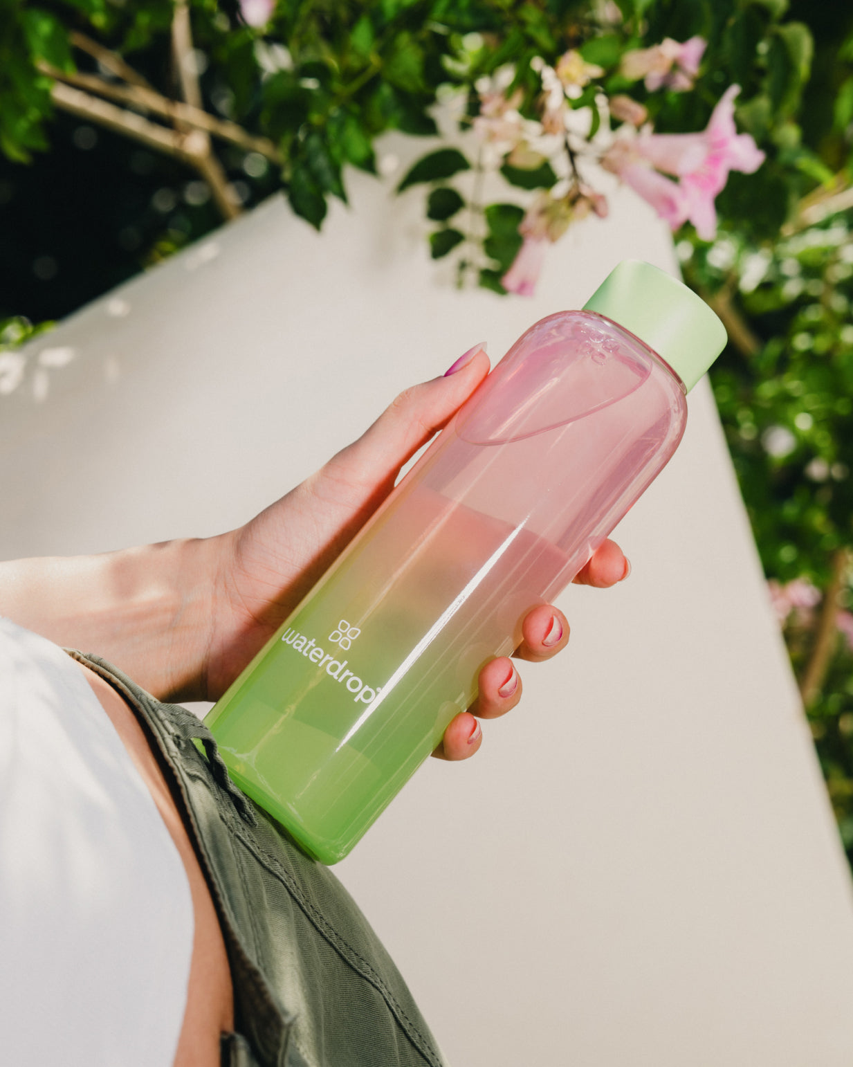 A hand holding the Summer Glass, a high-quality borosilicate bottle with a limited edition ombre design, ideal for pairing with waterdrop® Microdrinks.