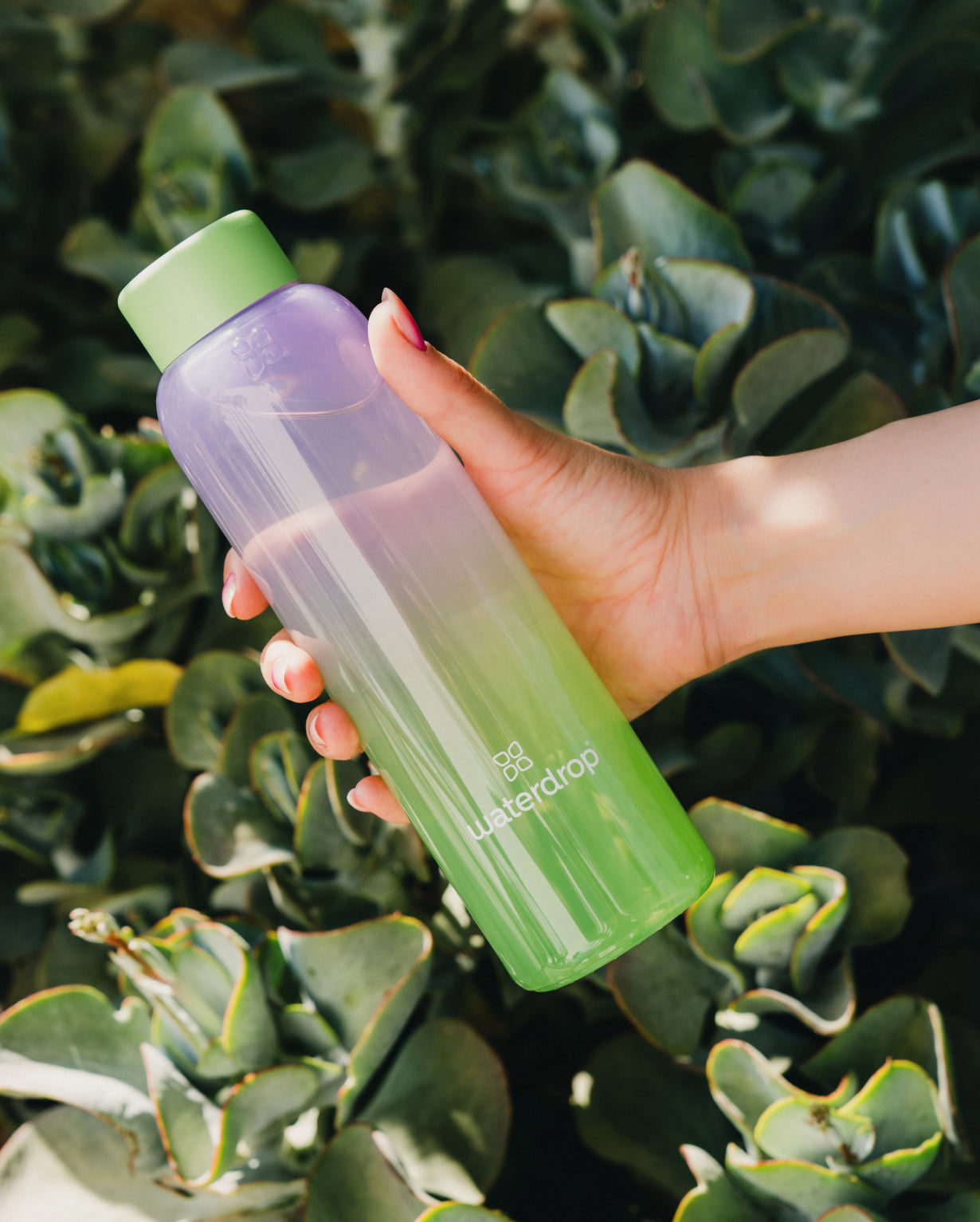 Hand holding the Summer Glass, a borosilicate glass bottle with an ombre design, perfect for pairing with Microdrinks from waterdrop®.