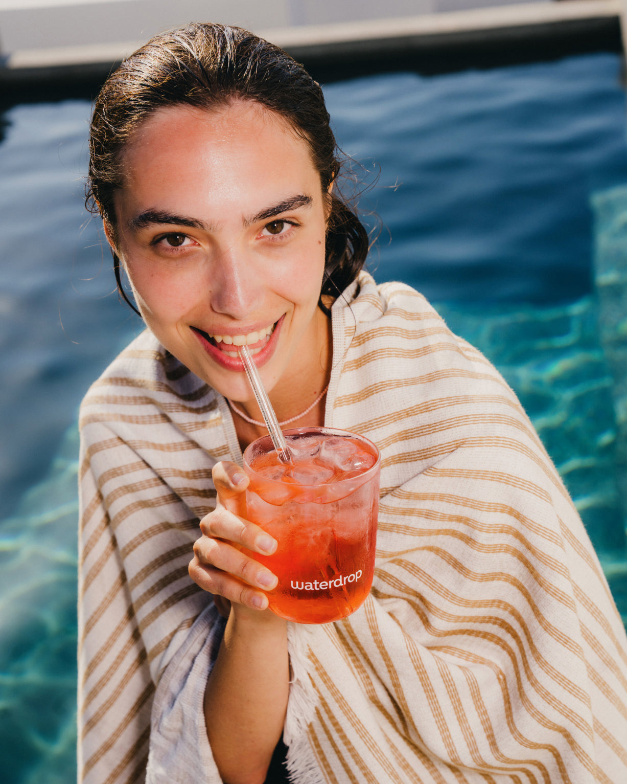 A woman wrapped in a blanket enjoys ICE TEA RASPBERRY through a straw, highlighting the refreshing, sugar-free raspberry drink.