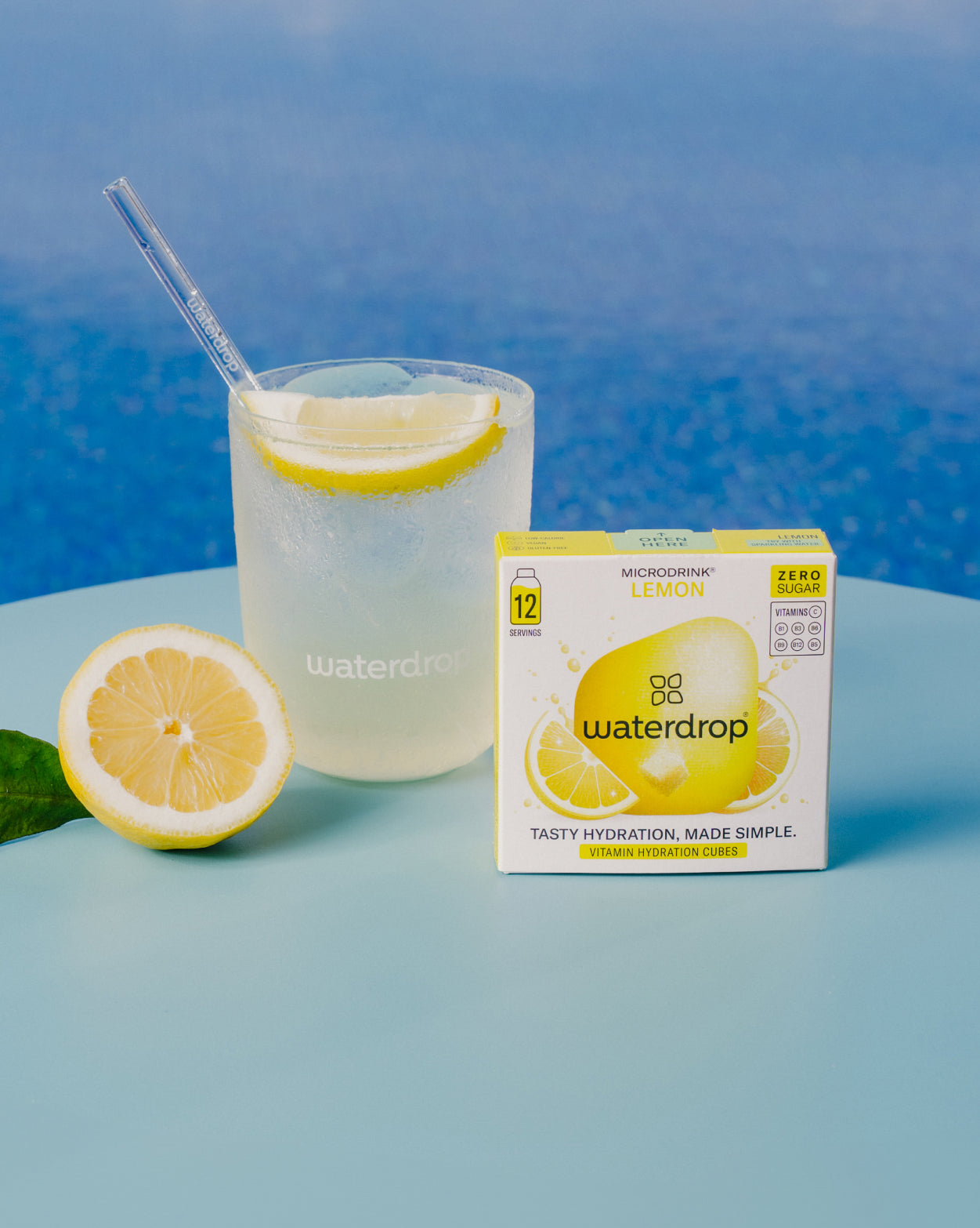 LEMON citrus concentrate next to a waterdrop® hydration cube box, a glass of lemon water, and a halved lemon. Perfect for tangy, sugar-free refreshment.