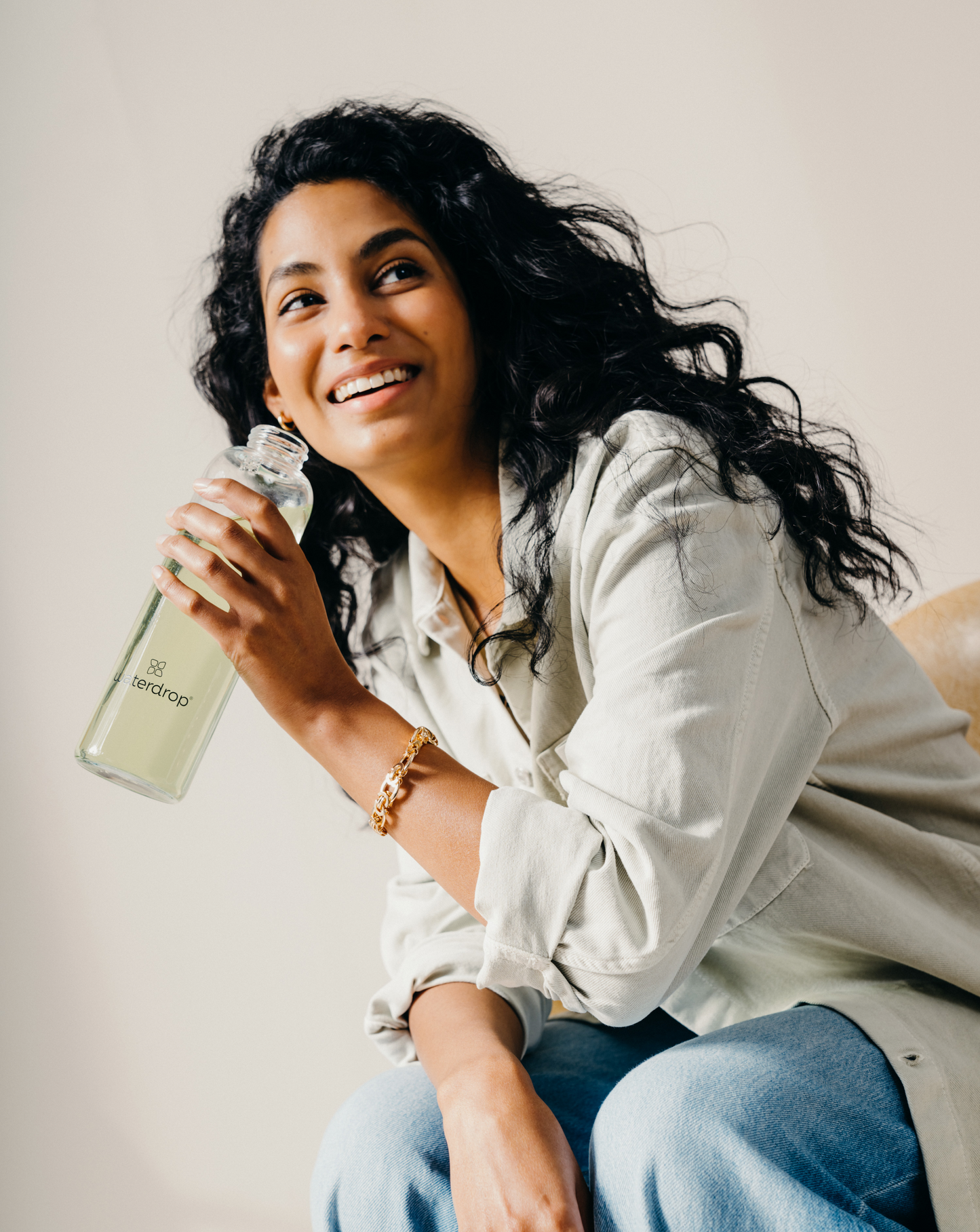A woman holding a Clear Glass Bottle, showcasing its minimalist design and transparency.