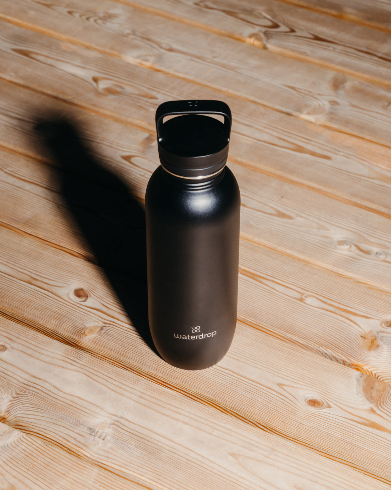 All-Purpose Ultralight Bottle with Straw Lid on a wooden surface, showcasing its sleek, lightweight design ideal for hiking and daily use.