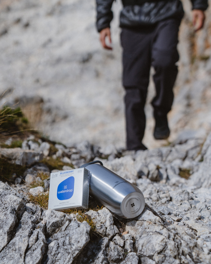 Microlyte Set on rocky terrain next to a white box, showcasing four flavors for hydration and performance enhancement.