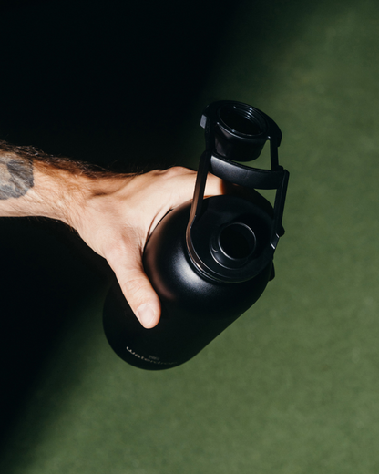 Hand holding the All-Purpose Thermo bottle with Swing Lid, showcasing its vacuum-insulated design for extended cold refreshment.