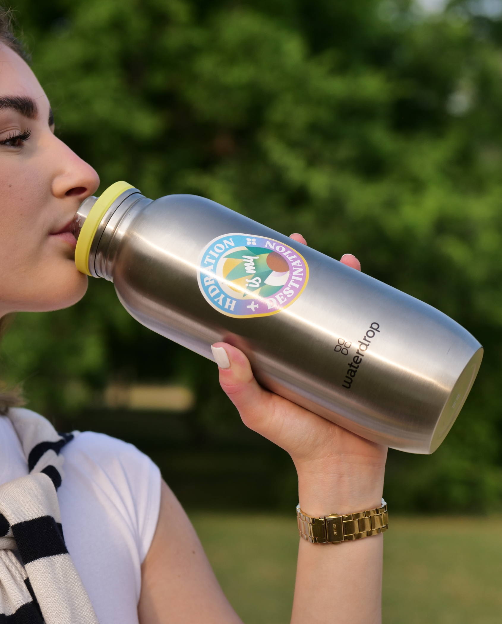 A woman drinking from a waterdrop® bottle with a Limited Edition Design bottle sticker.