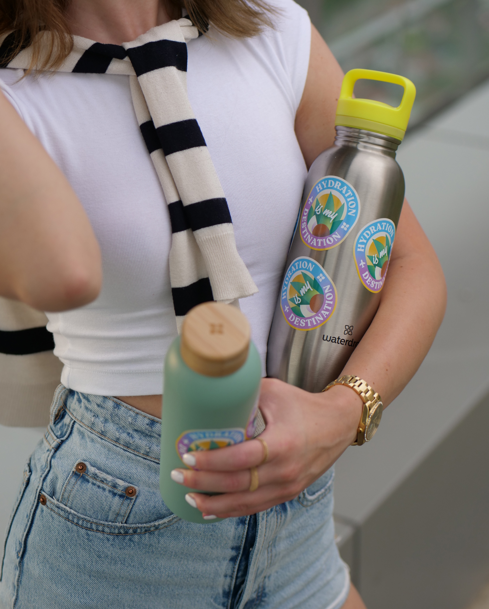 Woman holding a branded water bottle adorned with a limited edition bottle sticker, emphasizing hydration and style.