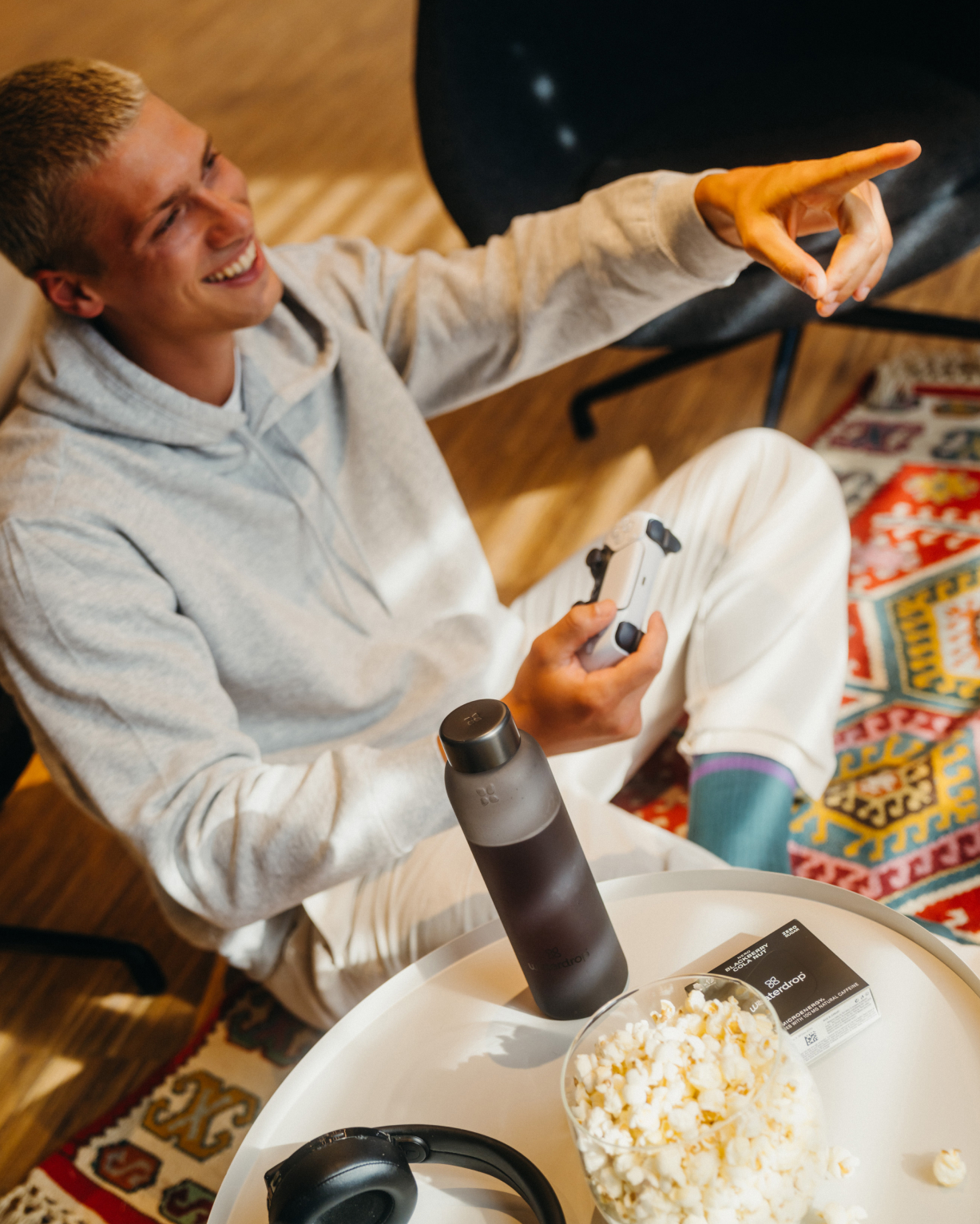 Twin Pack Microenergy: A man enjoys gaming while holding a video game controller, with a bottle of Microenergy nearby.