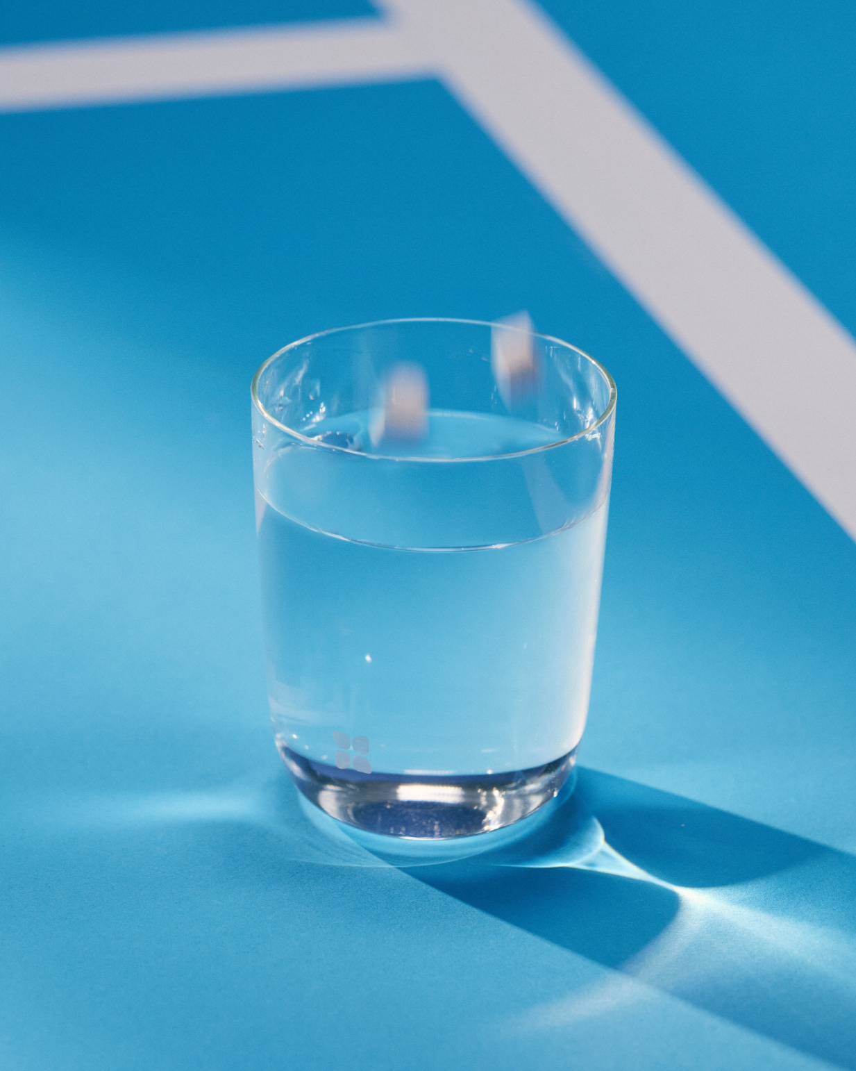SILA Grapefruit electrolyte drink in a glass, placed on a blue surface.