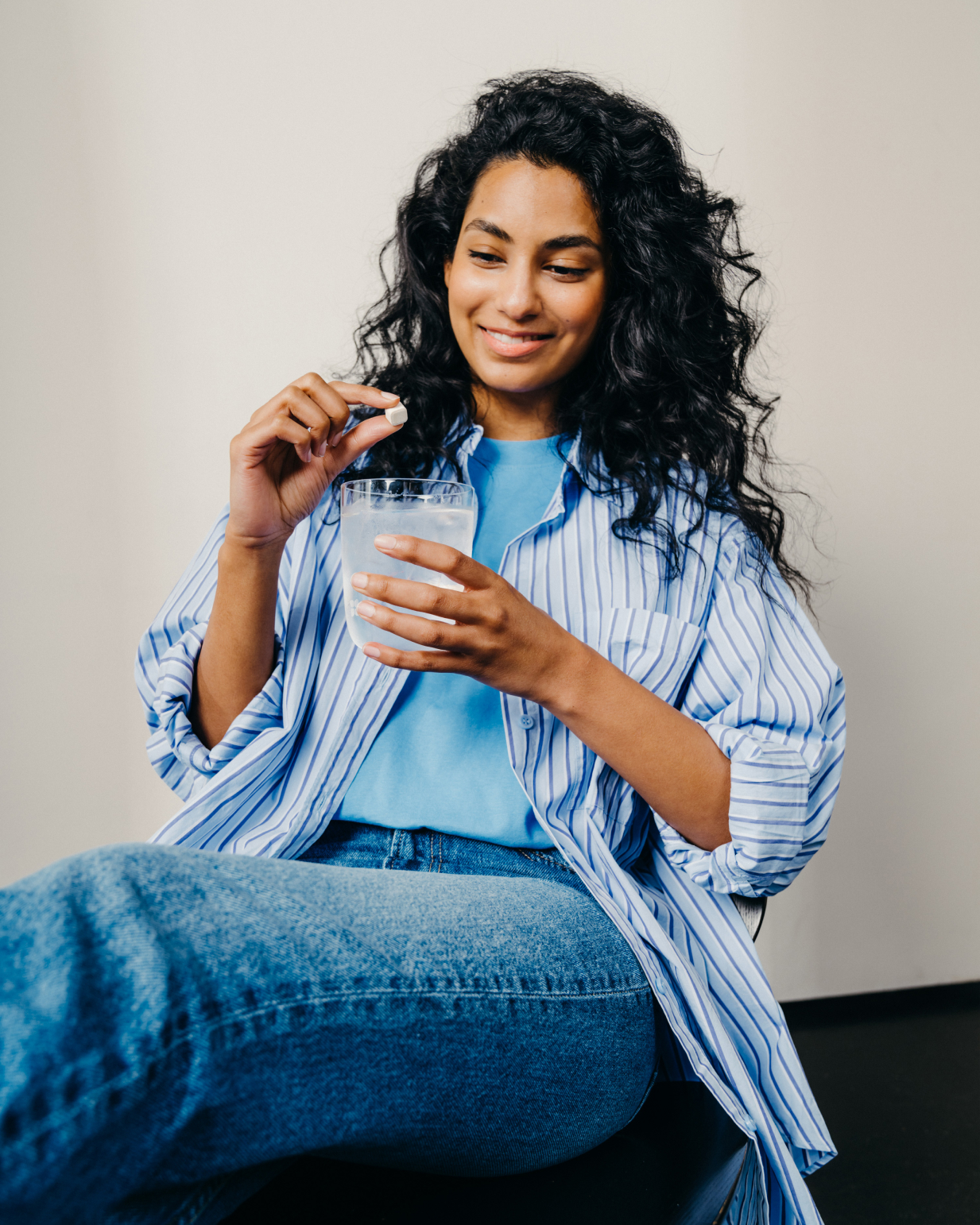 Woman holding a Clear Glass filled with water and a pill, showcasing waterdrop®'s distinct, functional borosilicate glass for hydration solutions.