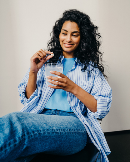Woman holding a Clear Glass filled with water and a pill, showcasing waterdrop®'s distinct, functional borosilicate glass for hydration solutions.