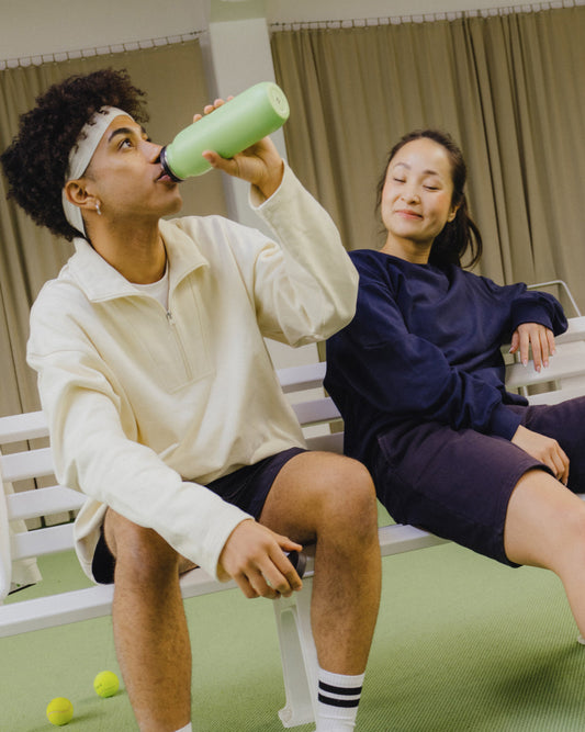 Man drinking from an All-Purpose Ultralight · Loop Lid green bottle, highlighting its ease of use and portability for hydration.