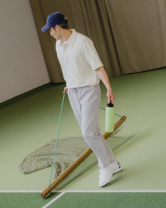 Man holding the All-Purpose Thermo · Loop Lid water bottle and a net, showcasing its size and practical loop handle.