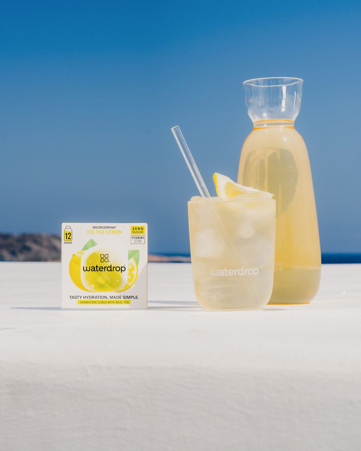 Bottle and glass of ICE TEA LEMON beside its box, ready to dissolve in water for a refreshing lemon and green tea drink.