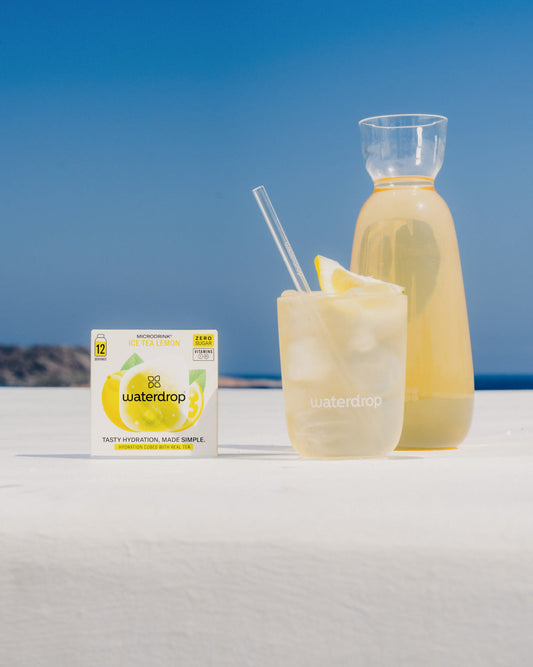 Bottle and glass of ICE TEA LEMON beside its box, ready to dissolve in water for a refreshing lemon and green tea drink.