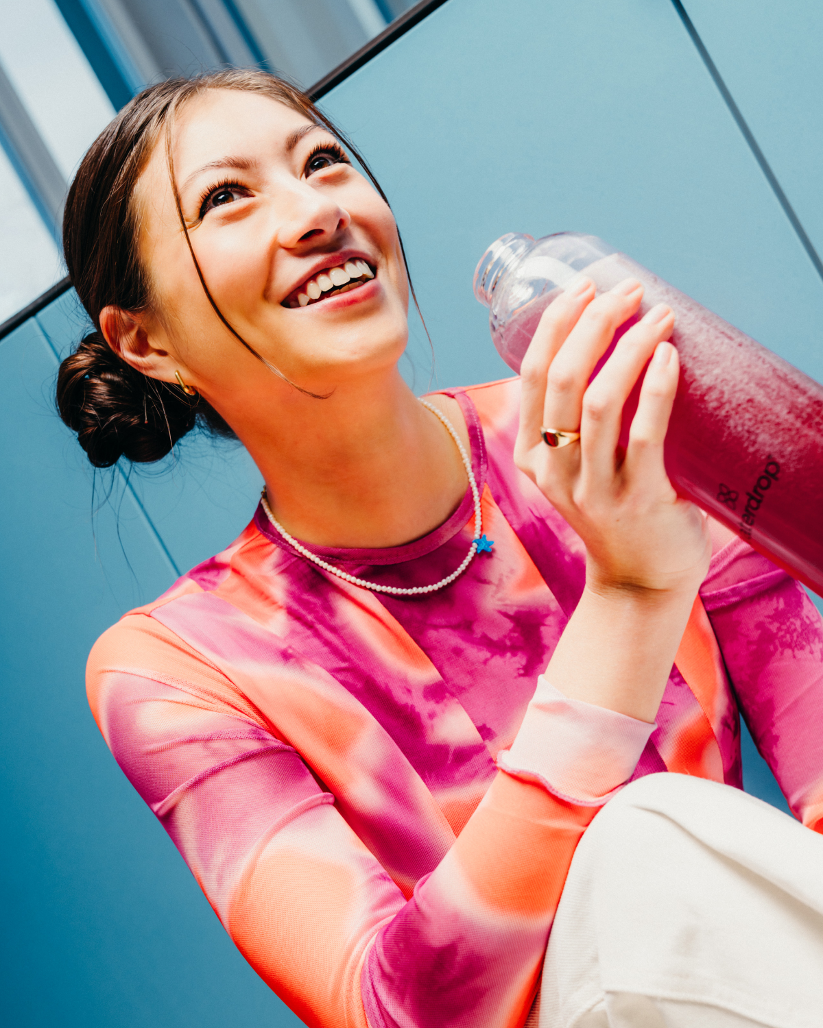 A woman smiling and holding a bottle of Microdrink BLACKBERRY, emphasizing its wholesome blend of BLACKBERRY microdrink , blueberry, and apple.